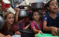 Palestinian children gather to receive cooked meals from a food distribution centre in the Nuseirat refugee camp in central Gaza