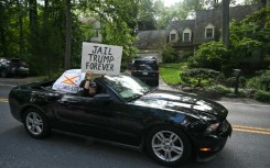 Protestors holding signs drive past the home of John Bolton, President Donald Trump's former national security adviser