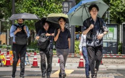 People shield themselves from the hot sun with umbrellas in Tokyo on August 27, 2025