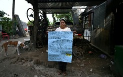 Juana Fuentes, 54, holds a sign addressed to President Nayib Bukele calling for the release of her son Nelson Antonio Fuentes, 23, imprisoned since April 2022