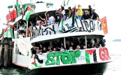 People aboard a boat wave Palestinian flags as they arrive to take part in a demonstration in support of Gaza at the Venice Lido