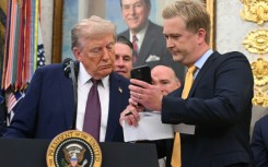 Fox News reporter Peter Doocy shows US President Donald Trump his phone during an Oval Office press conference