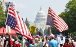 Demonstrators hold inverted US flags near the US Capitol during the "We Are All DC" national march calling for an end to the deployment of National Guard troops in Washington, DC