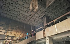 Locals look at the charred remains of the ravaged Parliament building in Kathmandu
