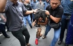 A protester suspected of clashing with police is arrested near the presidential palace in Manila on Sunday
