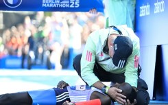 Kenya's Rosemary Wanjiru is tended to by a helper, having collapsed after crossing the finish line first.