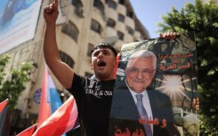 A Palestinian chants slogans in Ramallah while holding a portrait of Palestinian Authority president Mahmud Abbas