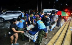 Police assist injured residents as they are brought to the hospital in Bogo City, Cebu province, central Philippines