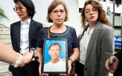 The trial began just three days ago with an examination of witnesses, including Lim Kimya's widow, Anne-Marie Lim (centre, holding a photo of Lim Kimya)