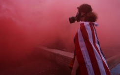 A protester stands in the haze from a smoke grenade outside of a downtown Portland U.S. Immigration and Customs Enforcement (ICE) facility