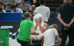 Novak Djokovic wipes his face as he receives medical attention