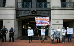 Demonstrators protest outside of the Albert V. Bryan United States Courthouse ahead of the arraignment of former FBI director James Comey