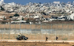 Israeli army soldiers walk towards an armoured vehicle at a position along the border fence with the Gaza Strip in southern Israel