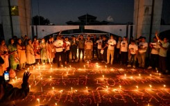 Nepalis lit candles outside the fire-damaged parliament building on Thursday, one month after anti-corruption protests toppled the government and left dozens dead