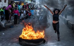 A protester runs past a burning tire used as a barricade during clashes with Madagascar security forces on October 9, 2025
