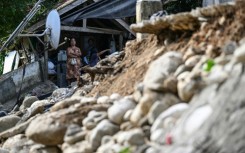 A woman looks at a damaged house in Manay on October 11, 2025, after two powerful quakes struck off the southern Philippines on October 10