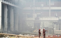 Firefighters inspect the fire-damaged cargo terminal of Hazrat Shahjalal International Airport in Dhaka on October 19, 2025, a day after the blaze