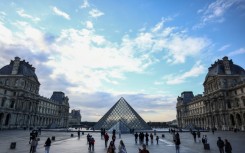Tourists stroll near the Louvre Pyramid, designed by Chinese-US architect Ieoh Ming Pei, at the entrance to the world-renowned Paris museum, which said it was shutting its doors after a break-in