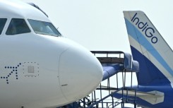 Ground staff walk past an IndiGo airlines aircraft taxiing in the apron at the Netaji Subhash Chandra Bose International Airport in Kolkata in February 2024