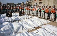 Civil Defense members stand by after laying out body bags containing the remains of members of the Shahebar family, who were buried in temporary graves, as they are brought to a cemetery in Gaza City