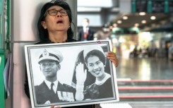 Thai mourner Kanjana Malaithong holds a portrait former queen Sirikit and king Bhumibol Adulyadej as she weeps at Chulalongkorn Hospital in Bangkok