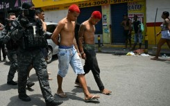 Police officers escort suspects arrested during the raid