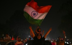 Fans wave flags as they celebrate India's victory in New Delhi