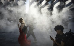 People walk under a misting system on a hot day in Tokyo earlier this year, which is on track to become one of the hottest in recorded history, according to the UN