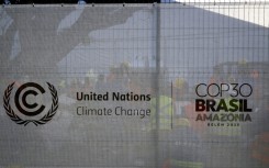 Workers rest behind a fence bearing the COP30 logo at a construction site in the City Park of the COP30, the United Nations Climate Change Conference in Belem, Para State, Brazil on November 3, 2025