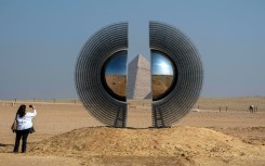 A woman takes a picture of the art installation "The Shen" by artist by Mert Ege Kose during the fifth edition of the "Forever is Now" art exhibition by Art d’Egypte at the Giza pyramids necropolis