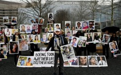 A man stands before photographs of victims of the Boeing 737 MAX crash in Ethiopia in March 2019, at a protest outside the US aircraft manufacturer's office in Arlington, Virginia