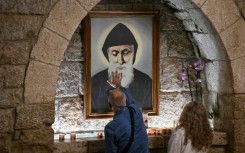 Pilgrims in front of a portrait of Saint Charbel at the monastery of Saint Maron in Lebanon's mountain village of Annaya