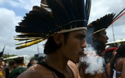 A Munduruku Indigenous man of the Ipereg Ayu movement smokes during a protest outside the COP30 UN Climate Change Conference in Belem