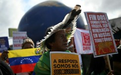 Indigenous people hold signs reading "The answer is us" and "End of fossil fuels, no mining in our territories" during a march on the sidelines of the COP30 UN Climate Change Conference in Belem, Brazil