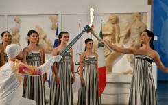 Greek actress Mary Mina (R), playing the role of the High Priestess, passed the Olympic flame to Greek rower Petros Gaidatzis