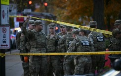 National Guard soldiers stand behind crime scene tape at a corner in downtown Washington where two National Guard soldiers were shot just blocks from the White House