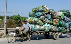Men on a motorbike pull a cart carrying plastic waste on the outskirts of Hanoi