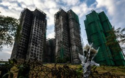 Flowers are seen in front of the Wang Fuk Court apartment blocks in the aftermath of the deadly November 26 fire in Hong Kong's Tai Po district on December 3, 2025