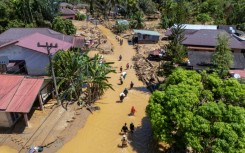 This picture shows an aerial view of villagers wading through the mudflow to find a shelter in the aftermath of flash floods in Tukka village, Central Tapanuli, North Sumatra province, on December 3, 2025