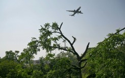 A commercial aircraft flies over the accident site of the Air India crash, still unresolved after six months
