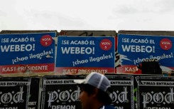 A person walks past posters supporting Chilean presidential candidate Jose Antonio Kast of the Republican Party in Santiago