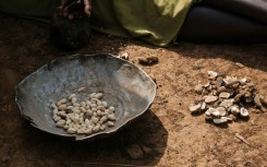 A woman sorts the fruit of the kudra plant to prepare a meal at a camp for displaced people in Kadugli