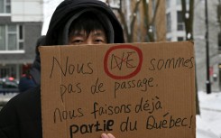 A pro-immigration demonstrator in Montreal, Canada holds a sign that reads in French: 'We're not just passing through, we're already part of Quebec'
