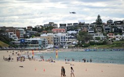 A police helicopter patrols over the Bondi Beach in Sydney as life gradually returns to normal following a deadly shooting attack