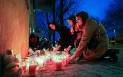 Women light candles at a makeshift memorial outside the Zagreb school where the stabbing happened