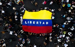 Venezuelans living in Argentina display a Venezuelan flag that reads "Freedom" as they celebrate the toppling of strongman Nicolas Maduro