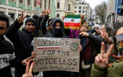 Protesters hold a placard reading "Voice for the voiceless" and the flag of Iran from before the 1979 revolution during a demonstration outside the Iranian Consulate in Istanbul
