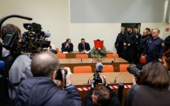 The defendant, partially identified as Farhad N., hides his face behind a folder at the start of his trial in Munich