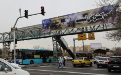 Cars drive under a banner that reads "This is not a protest" in Tehran
