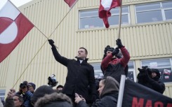 Greenland's prime minister Jens-Frederik Nielsen (L) holds a Greenlandic flag at a demonstration against US President Donald Trump's wish to take over the territory
